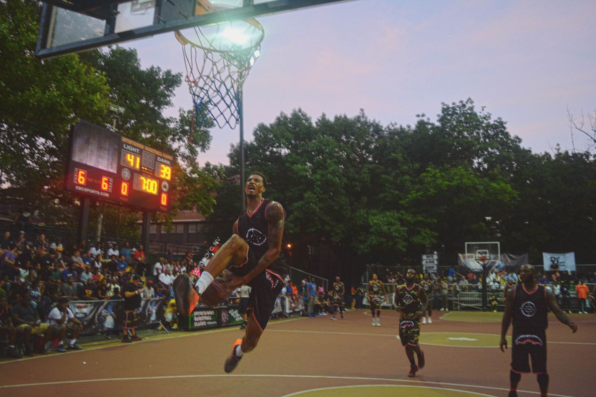 Crowd in the background, basketball player going up for a dunk with players behind him